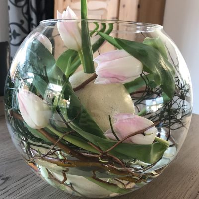 Struisvogelei in glazen bol met tulpen